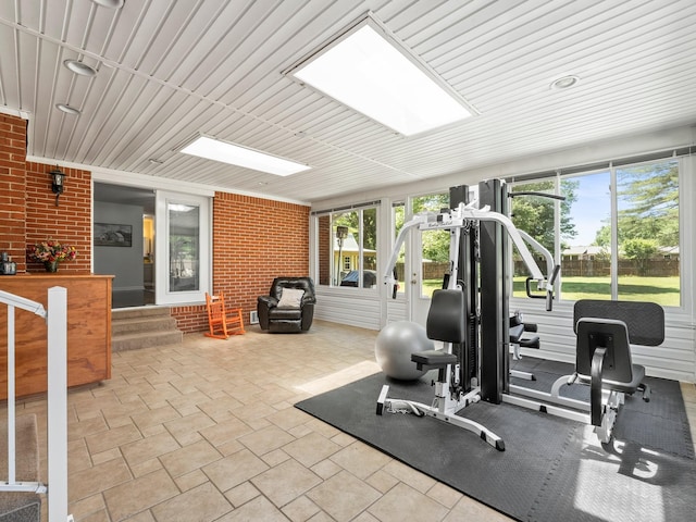 exercise room with brick wall, healthy amount of natural light, and a skylight