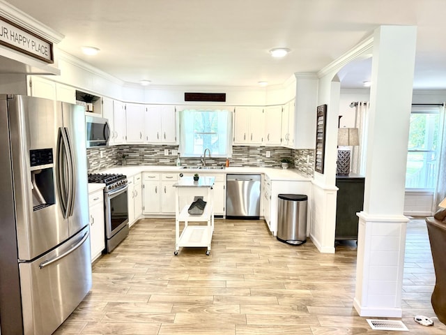 kitchen with stainless steel appliances, light wood-style floors, light countertops, a sink, and white cabinets