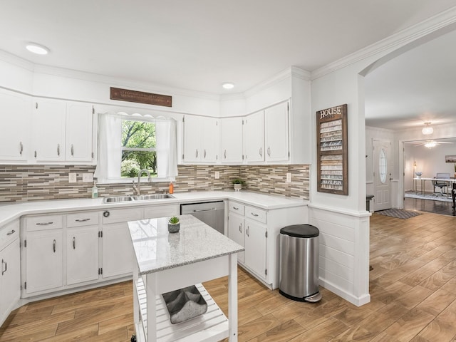 kitchen with a sink, white cabinets, ornamental molding, and light wood finished floors