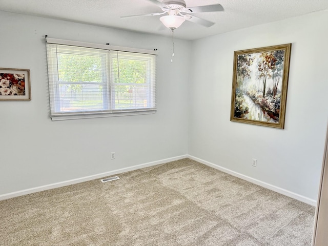 carpeted empty room with a ceiling fan and baseboards