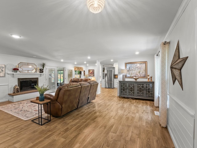 living room featuring crown molding, wood finished floors, a brick fireplace, recessed lighting, and a chandelier