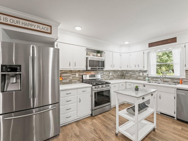 kitchen with appliances with stainless steel finishes, a sink, open shelves, light countertops, and ornamental molding