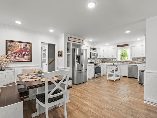kitchen featuring appliances with stainless steel finishes, light countertops, backsplash, a sink, and white cabinets