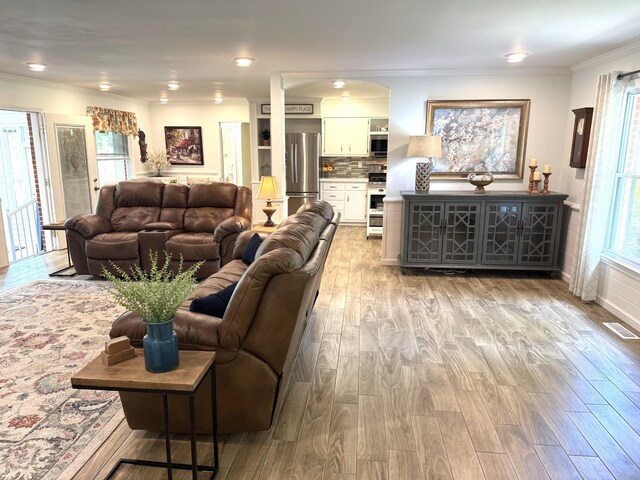 living area with wood finished floors and crown molding