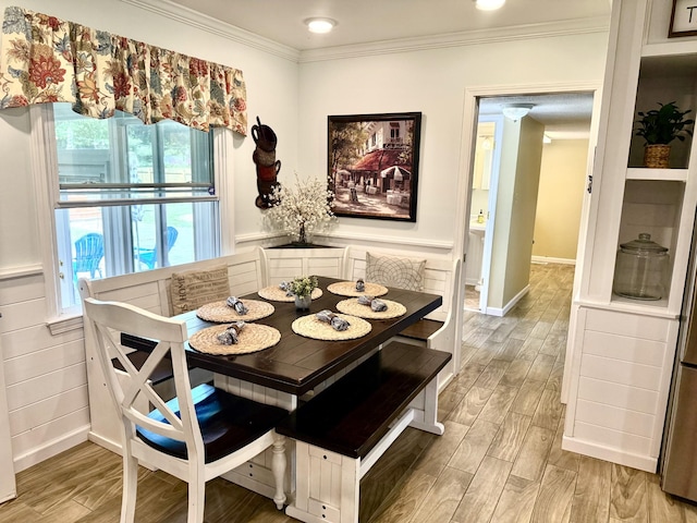 dining room featuring light wood-type flooring, crown molding, and baseboards