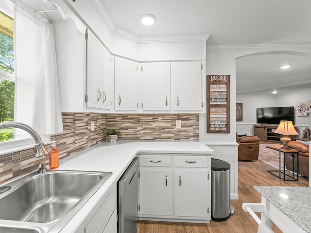 kitchen featuring a sink, dishwasher, white cabinetry, light countertops, and crown molding