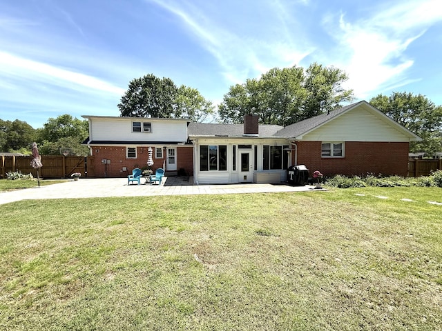 rear view of house featuring brick siding, a patio, a sunroom, and a chimney