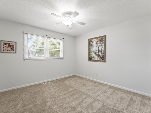 carpeted empty room featuring ceiling fan, a textured ceiling, and baseboards