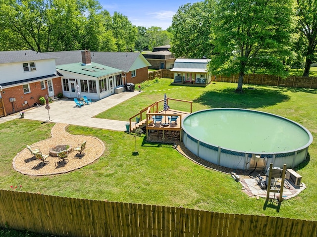view of swimming pool featuring a sunroom, a patio, an outdoor structure, and an outdoor fire pit