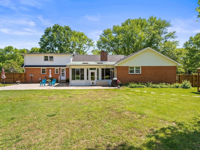 back of house featuring a patio, brick siding, a chimney, and a sunroom