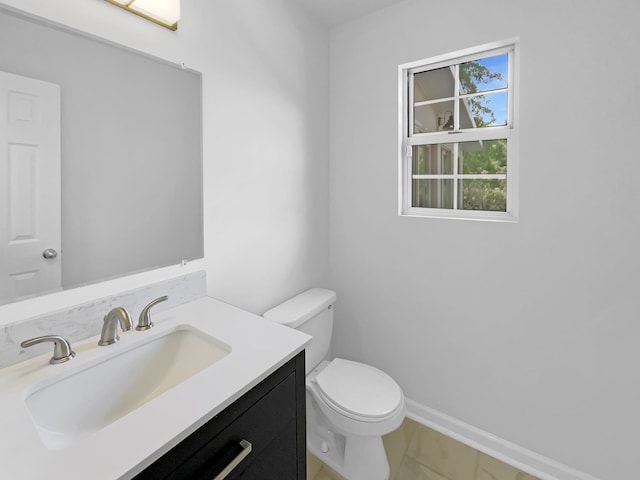 bathroom with toilet, vanity, marble look tiles, and baseboards