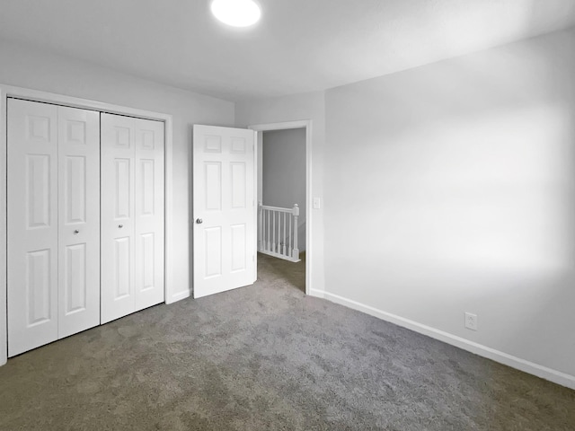 unfurnished bedroom with baseboards, carpet flooring, and a closet
