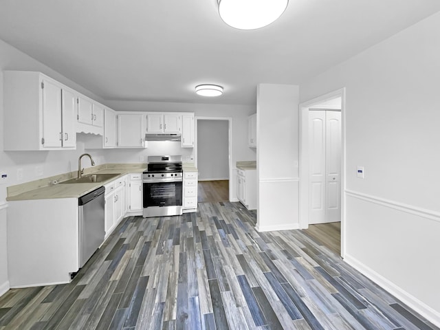 kitchen with stainless steel appliances, under cabinet range hood, dark wood-type flooring, and a sink