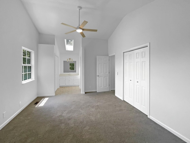unfurnished bedroom with carpet floors, high vaulted ceiling, baseboards, a closet, and ensuite bath