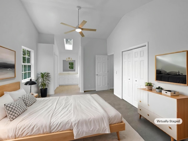carpeted bedroom featuring high vaulted ceiling, a closet, ensuite bath, baseboards, and a skylight