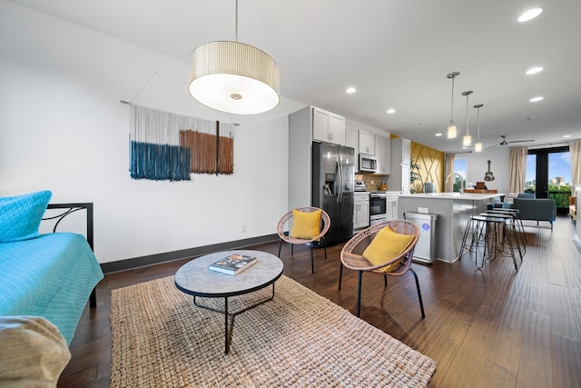 living room with recessed lighting, dark wood-type flooring, ceiling fan, and baseboards