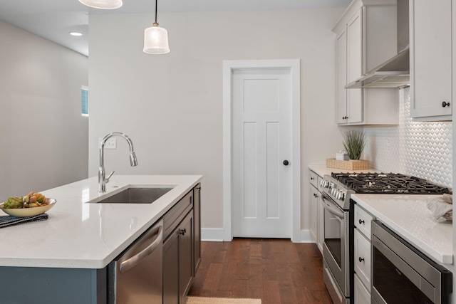 kitchen with a sink, appliances with stainless steel finishes, dark wood-style floors, decorative light fixtures, and backsplash
