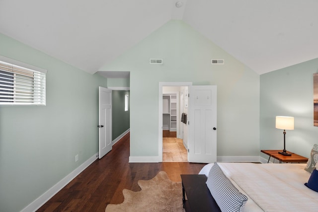 bedroom with wood finished floors, a walk in closet, high vaulted ceiling, a closet, and baseboards
