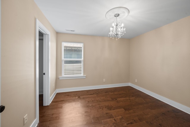 unfurnished room featuring a chandelier, dark wood-style floors, and baseboards