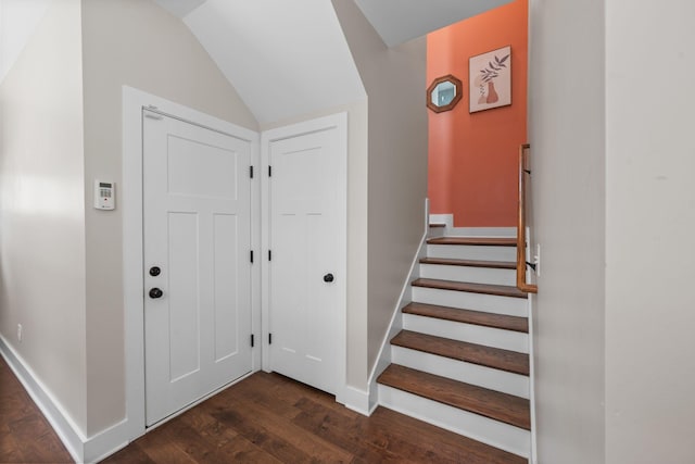 stairway with wood finished floors, lofted ceiling, and baseboards