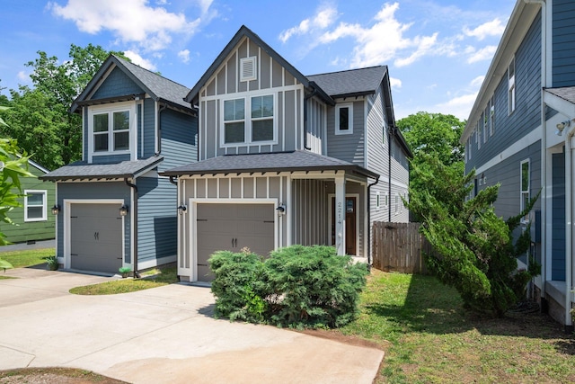 view of front of property with board and batten siding, a garage, concrete driveway, and fence