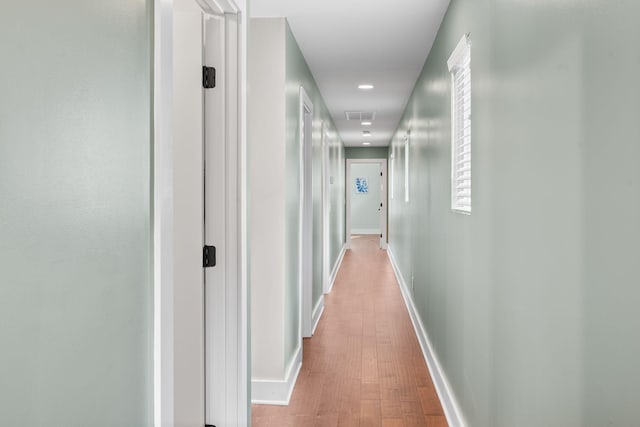 hallway featuring baseboards, wood finished floors, and recessed lighting