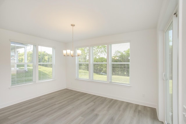 unfurnished dining area featuring a chandelier, light wood finished floors, and baseboards