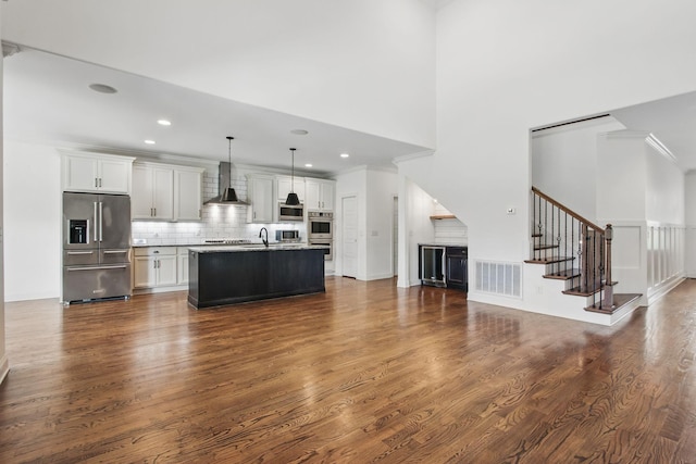 unfurnished living room with dark wood finished floors, stairs, a sink, recessed lighting, and ornamental molding