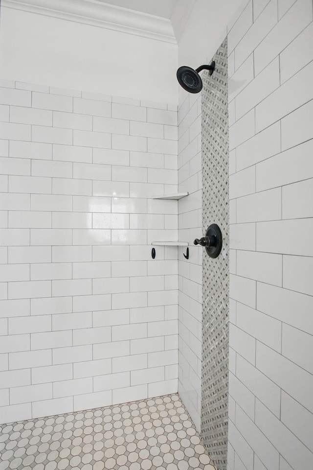 bathroom with ornamental molding and a tile shower