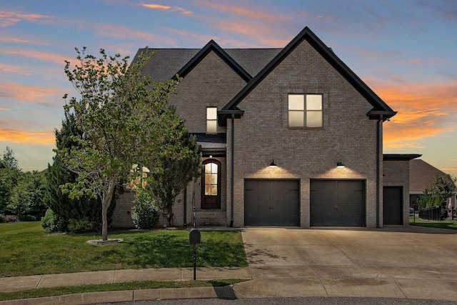 french country inspired facade with a lawn, brick siding, an attached garage, and concrete driveway