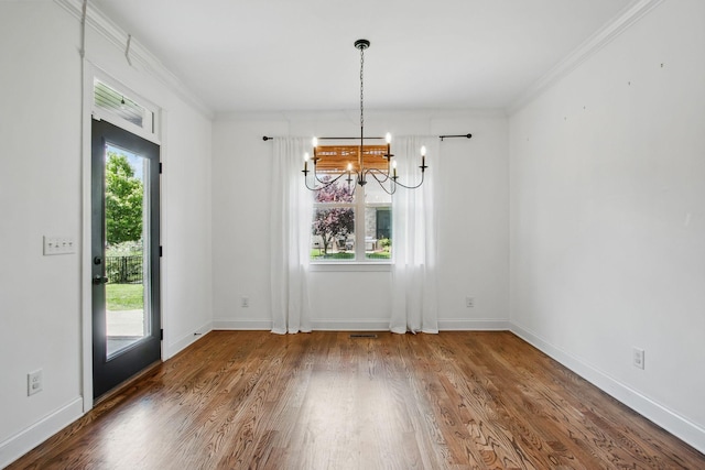 unfurnished dining area with a chandelier, wood finished floors, ornamental molding, and baseboards