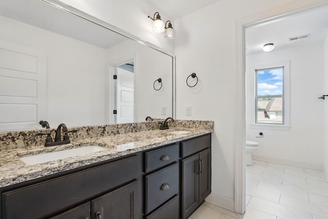 bathroom featuring baseboards, double vanity, and toilet