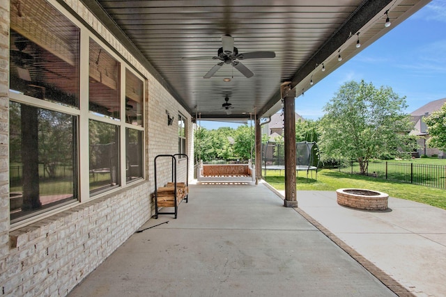 view of patio / terrace featuring a fire pit, a trampoline, and a ceiling fan