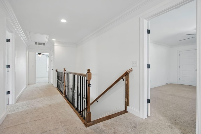 hall with attic access, an upstairs landing, carpet floors, crown molding, and baseboards