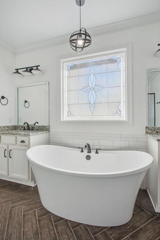 full bathroom featuring vanity, ornamental molding, a freestanding tub, and parquet floors