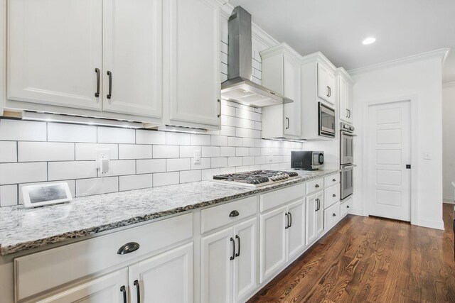 kitchen with wall chimney exhaust hood, stainless steel appliances, white cabinets, dark wood-style flooring, and crown molding