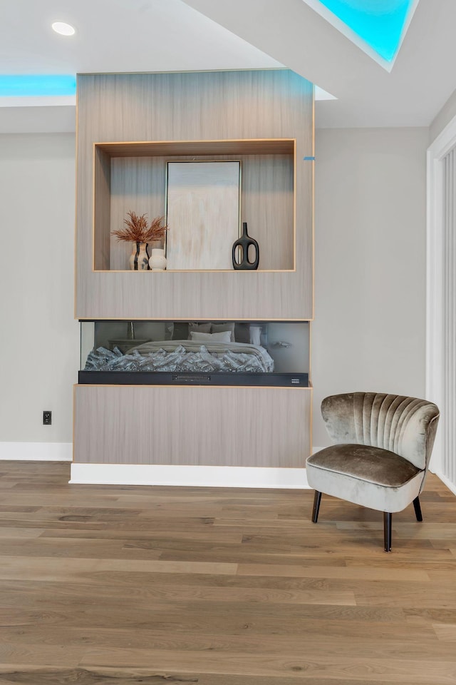 sitting room featuring wood finished floors, baseboards, recessed lighting, and a skylight