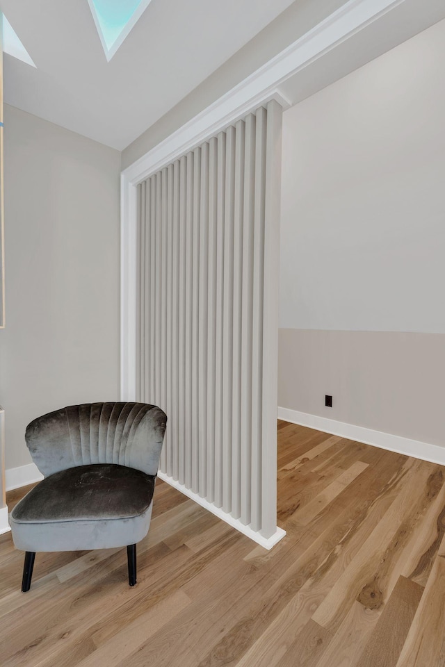 living area with wood finished floors, a skylight, and baseboards