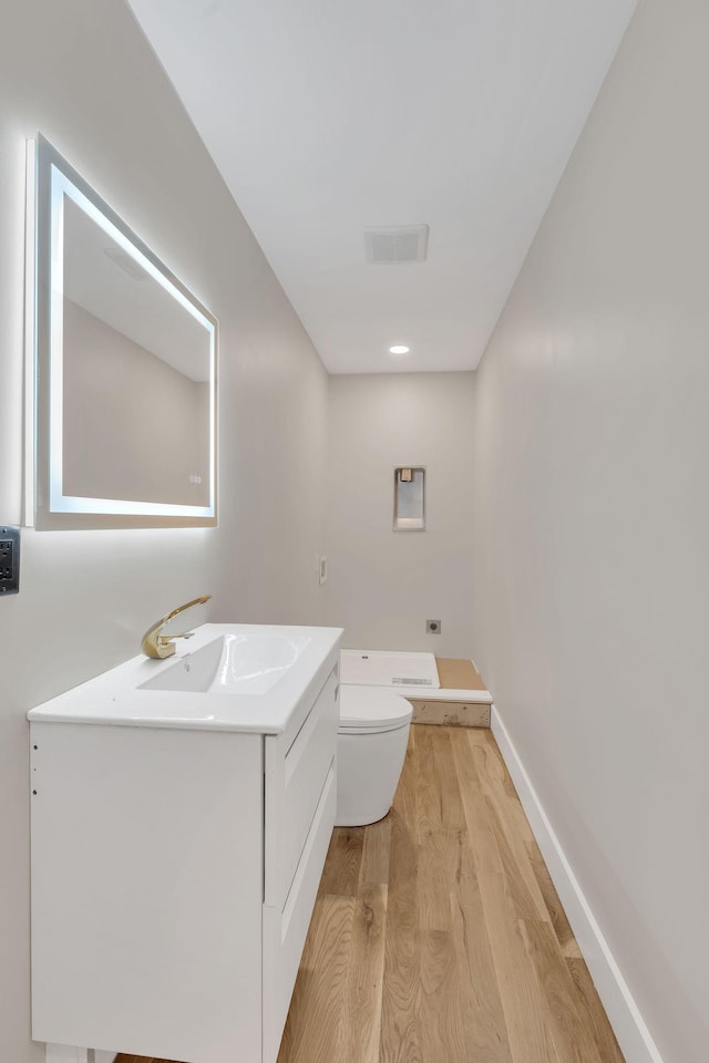 bathroom featuring toilet, wood finished floors, vanity, and baseboards