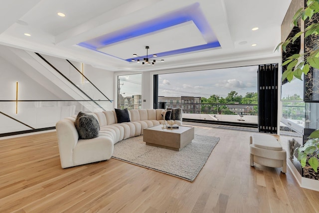 living area featuring wood finished floors, a chandelier, stairway, recessed lighting, and a tray ceiling