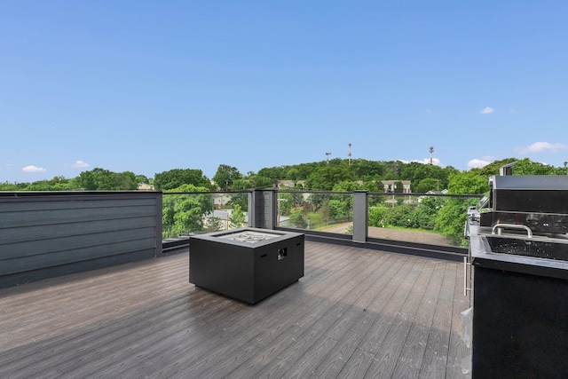 wooden deck with an outdoor fire pit and area for grilling