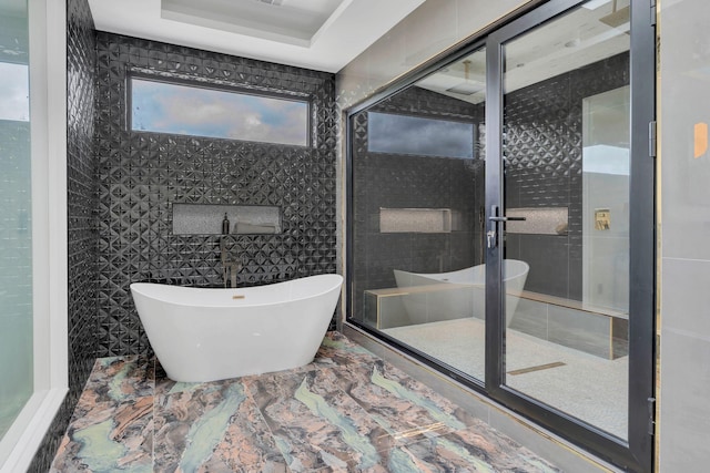 full bathroom featuring a freestanding tub and marble finish flooring