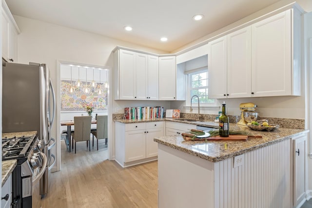 3060 Liberty Hills Dr, Franklin, TN 37067 - kitchen featuring stainless steel gas range oven, a sink, light wood-style flooring, light stone countertops, and white cabinetry