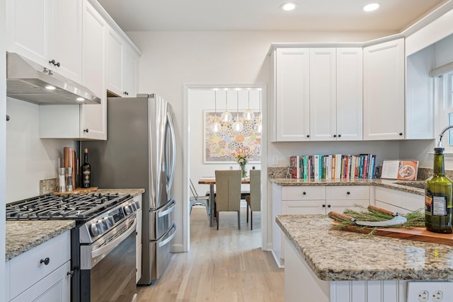 3060 Liberty Hills Dr, Franklin, TN 37067 - kitchen with stainless steel gas stove, under cabinet range hood, light wood-style flooring, white cabinetry, and light stone countertops
