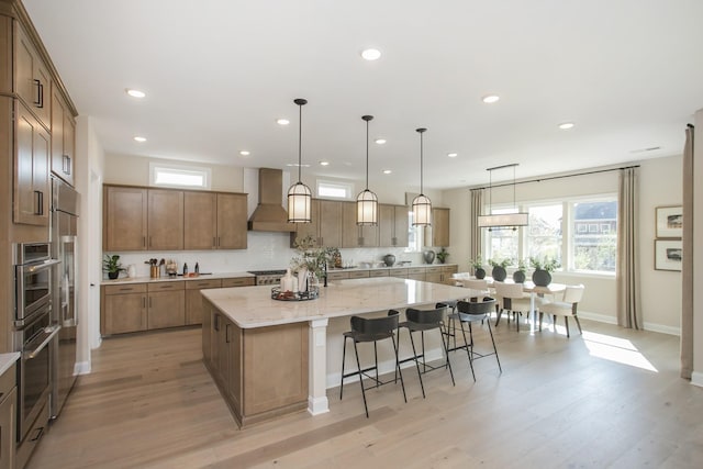 2955 Hunt Valley Dr, Spring Hill, TN 37174 - kitchen with wall chimney exhaust hood, a large island with sink, healthy amount of natural light, light wood-style flooring, and recessed lighting
