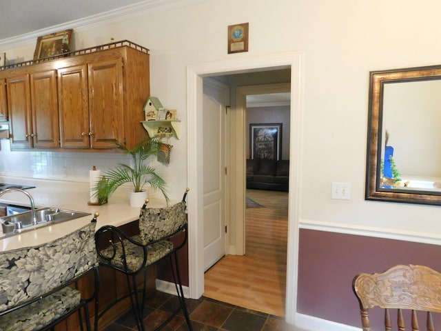 1129 Adam Dr, Cottontown, TN 37048 - kitchen with a sink, brown cabinets, crown molding, dark stone finish flooring, and light countertops