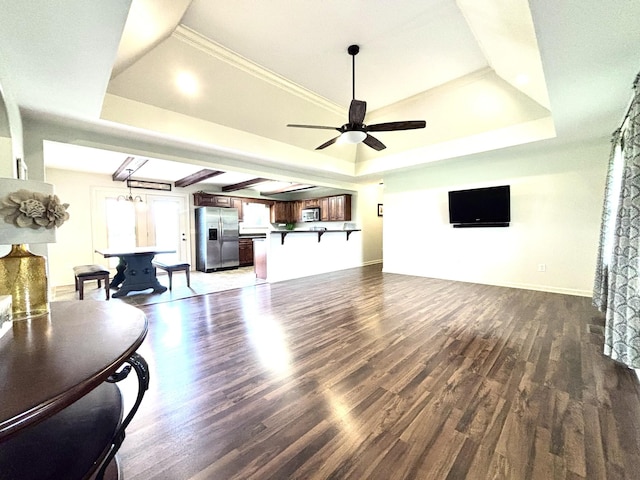 living room with a raised ceiling, wood finished floors, a ceiling fan, and baseboards
