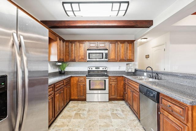 kitchen featuring appliances with stainless steel finishes, a sink, brown cabinetry, beam ceiling, and a peninsula