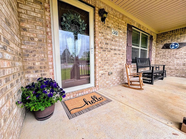 doorway to property featuring brick siding and covered porch