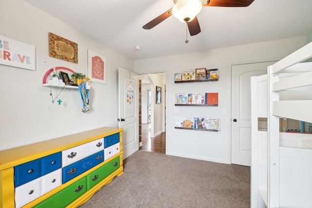 recreation room featuring a ceiling fan, carpet, and arched walkways
